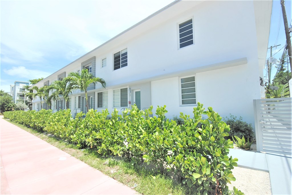 a white building with green bushes in front of it