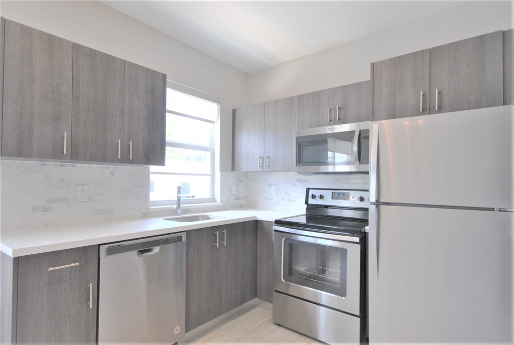 an empty kitchen with stainless steel appliances and a window