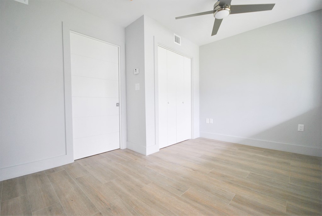 an empty room with white walls and a ceiling fan