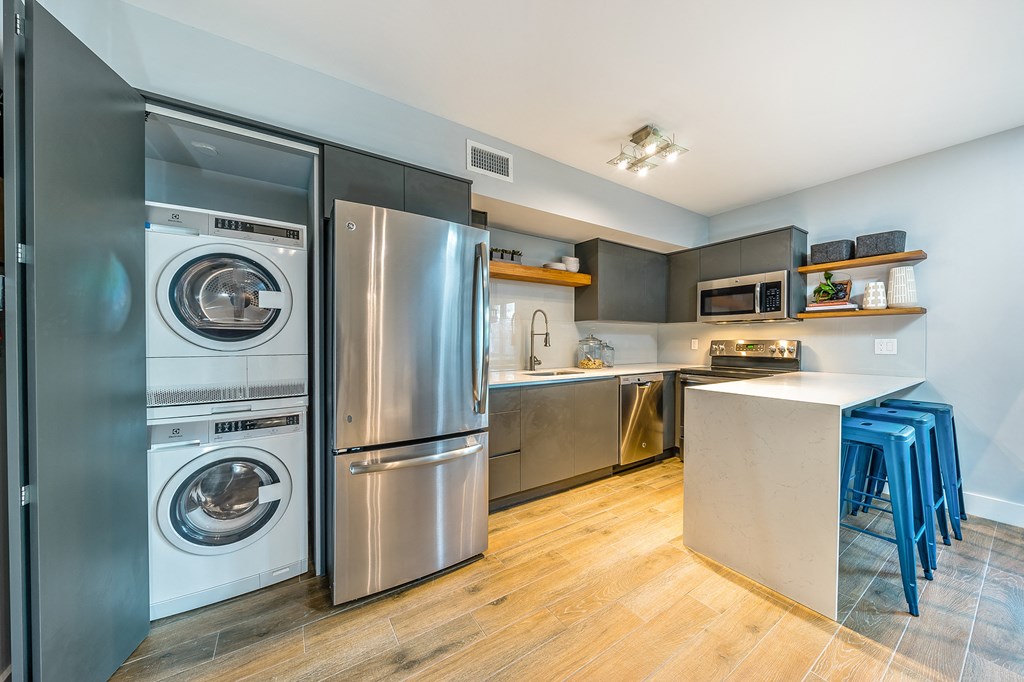 a kitchen with stainless steel appliances and a washer and dryer and a counter
