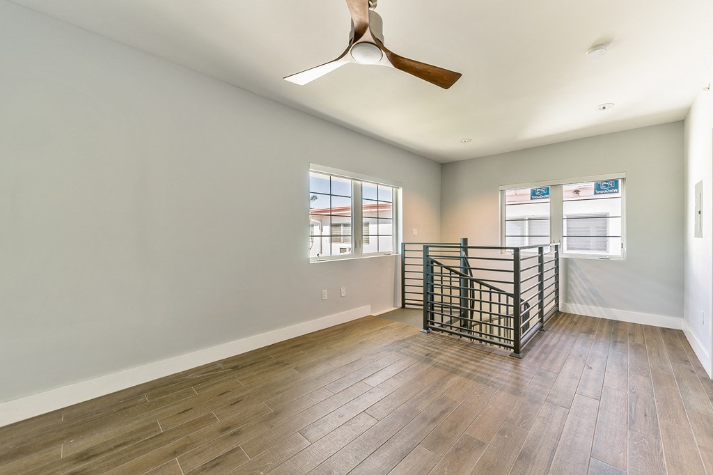 an empty living room with hardwood floors and a ceiling fan