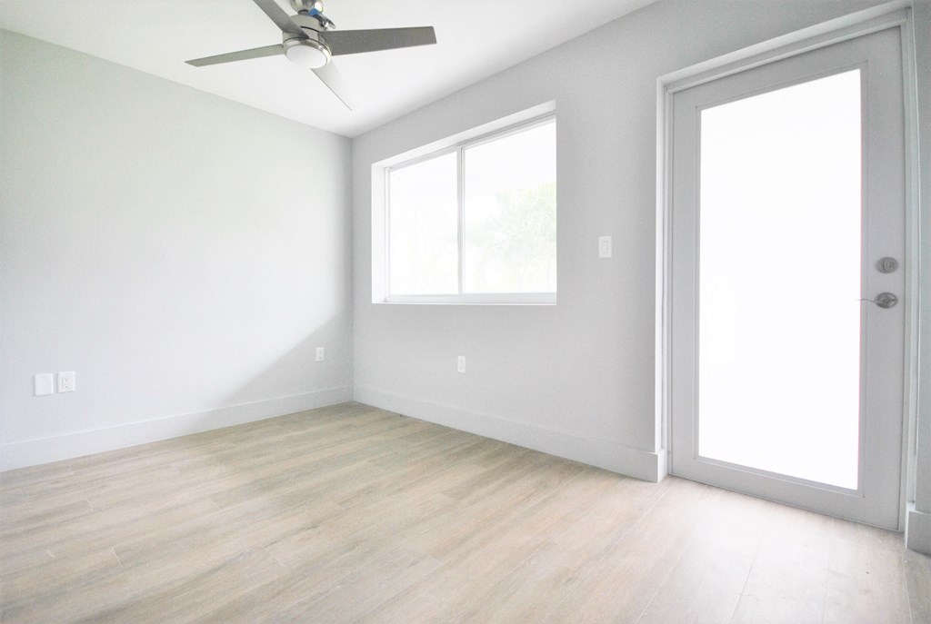 an empty room with white walls and a window and a ceiling fan