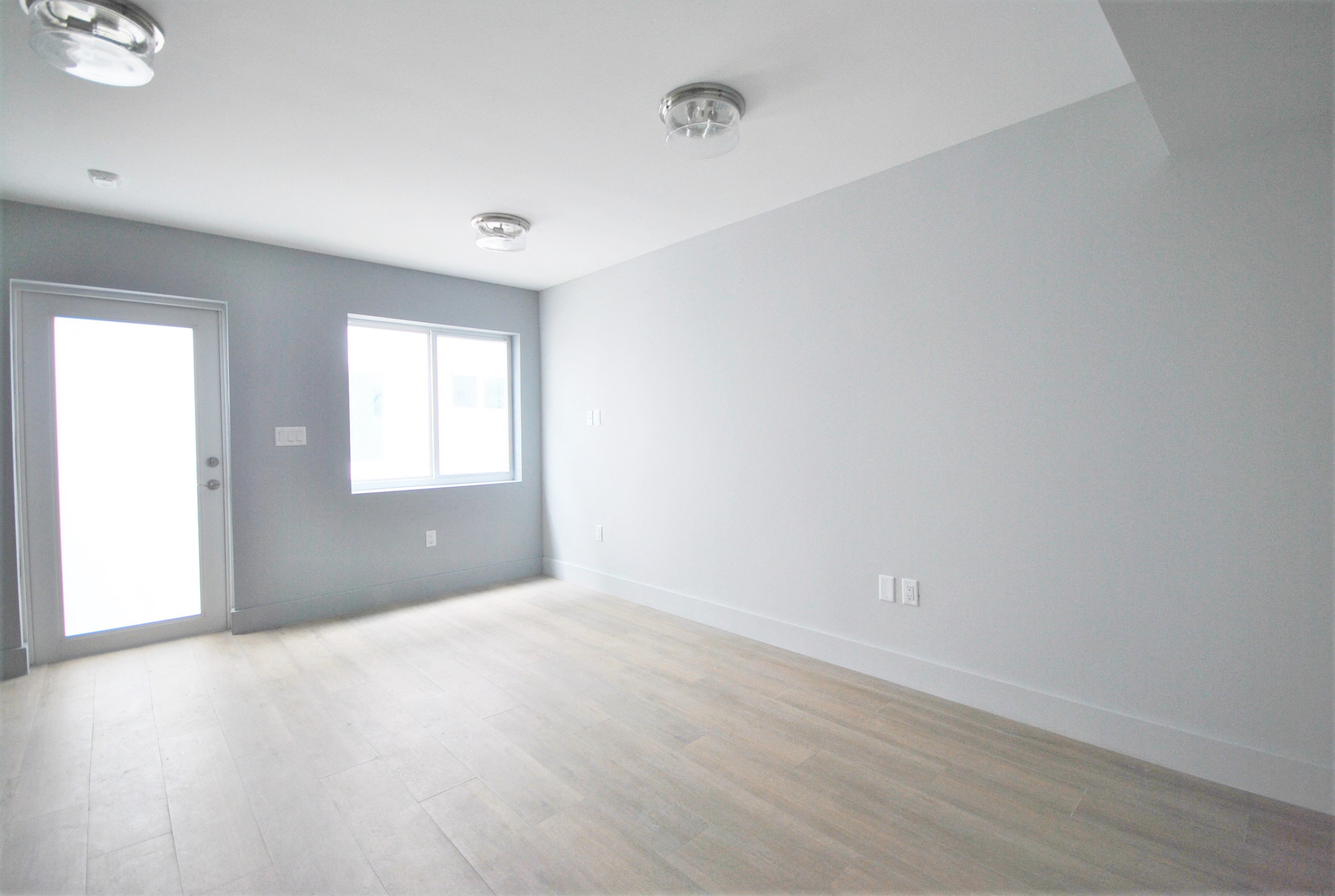 an empty living room with grey walls and a wooden floor