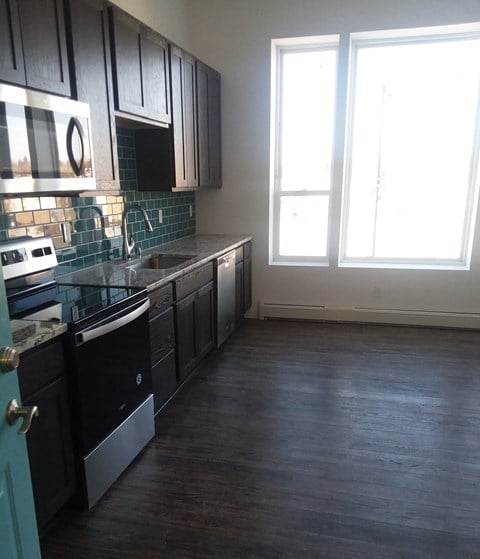 an empty kitchen with black appliances and wood floors