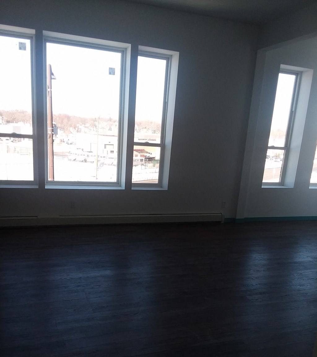 an empty living room with three large windows