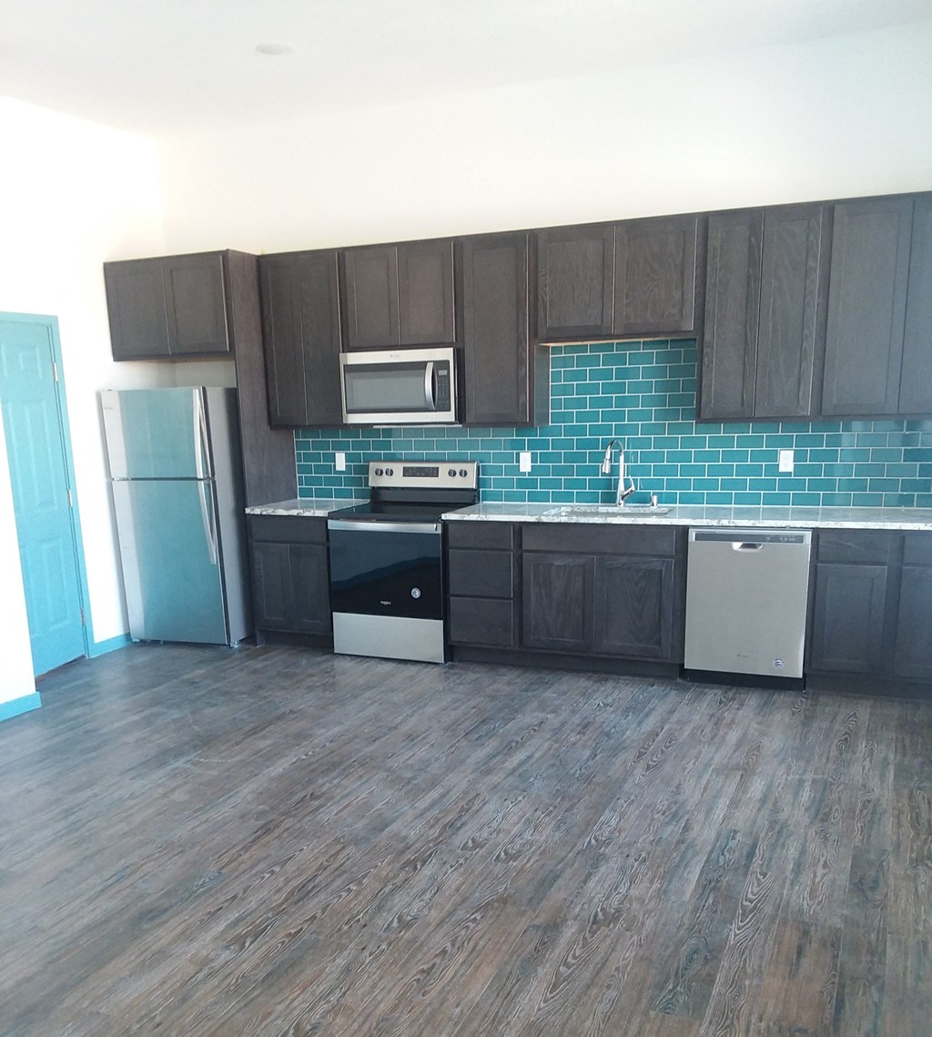 an empty kitchen with dark wood cabinets and blue tile