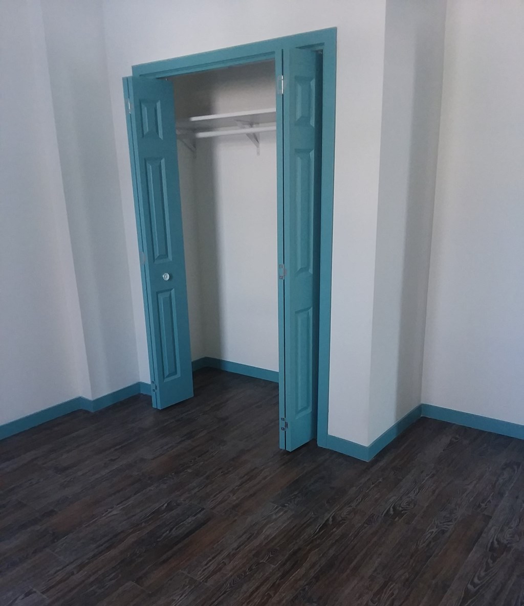 a closet in a room with wood floors and a blue closet door