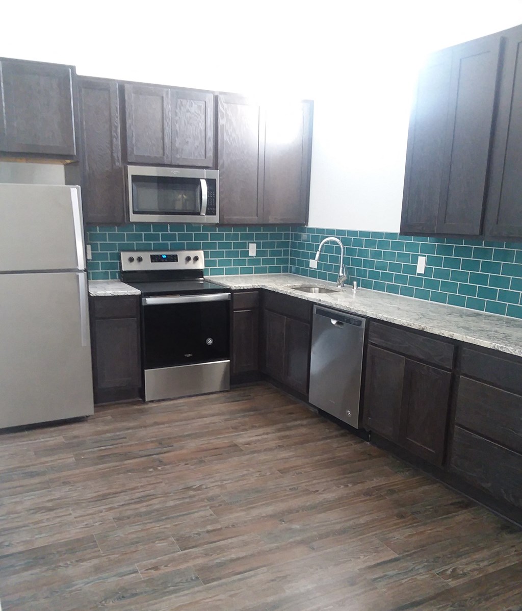 an empty kitchen with dark wood cabinets and white counter tops