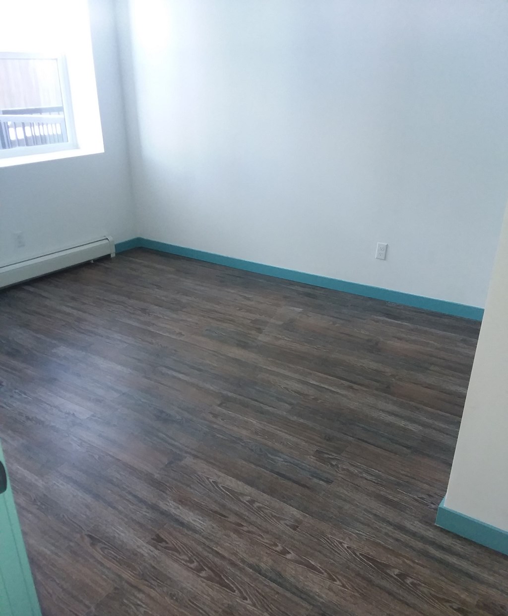 an empty room with wooden floors and a window