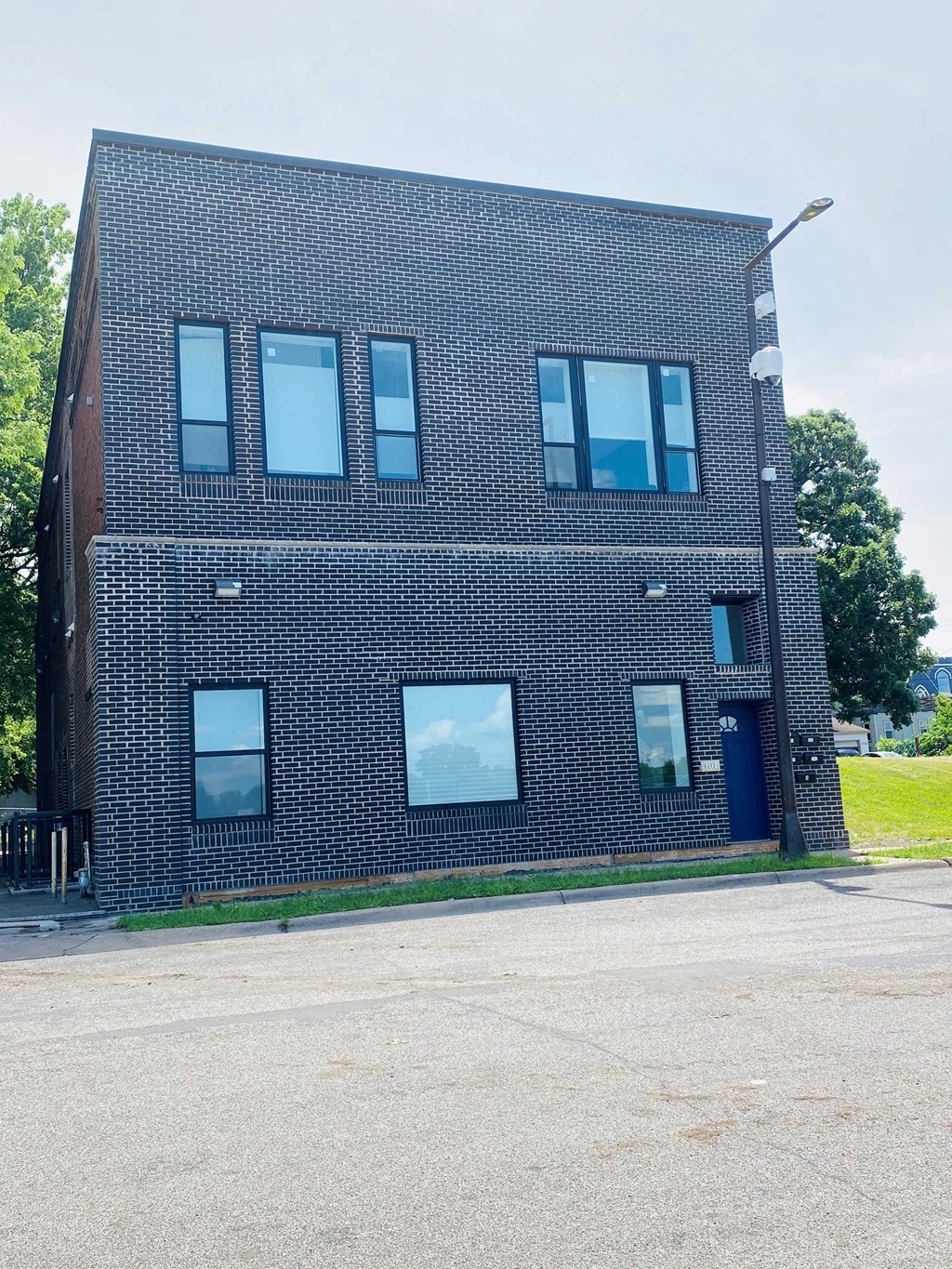 the front of a brick building with a blue door and windows