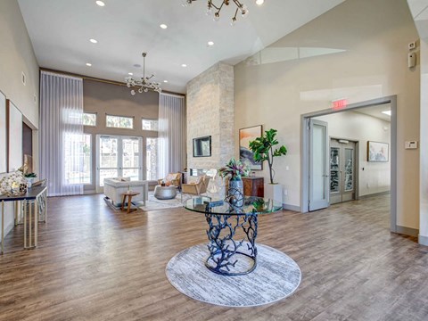 A modern living room with a glass coffee table and a chandelier.