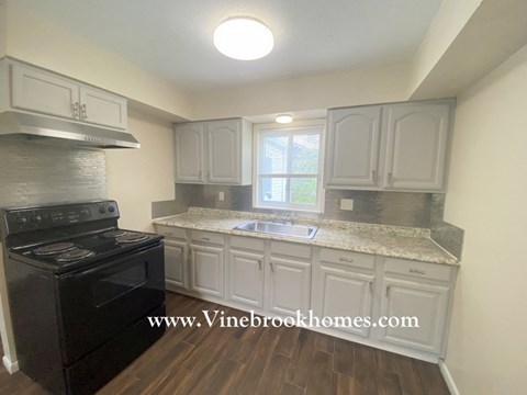 a kitchen with white cabinets and a stove and a sink