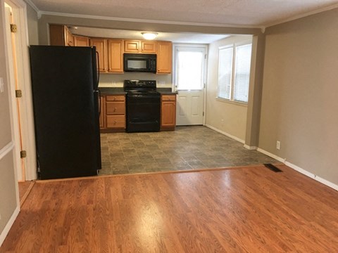 A kitchen with a black fridge, black stove, and wooden cabinets.