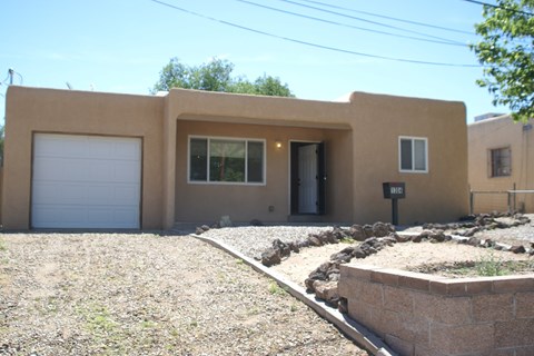 the front of a house with a gravel driveway and a white garage door