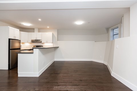 A kitchen with white cabinets and a wooden floor.