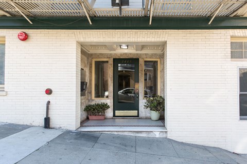 A white building with a black door and a red sign on the wall.
