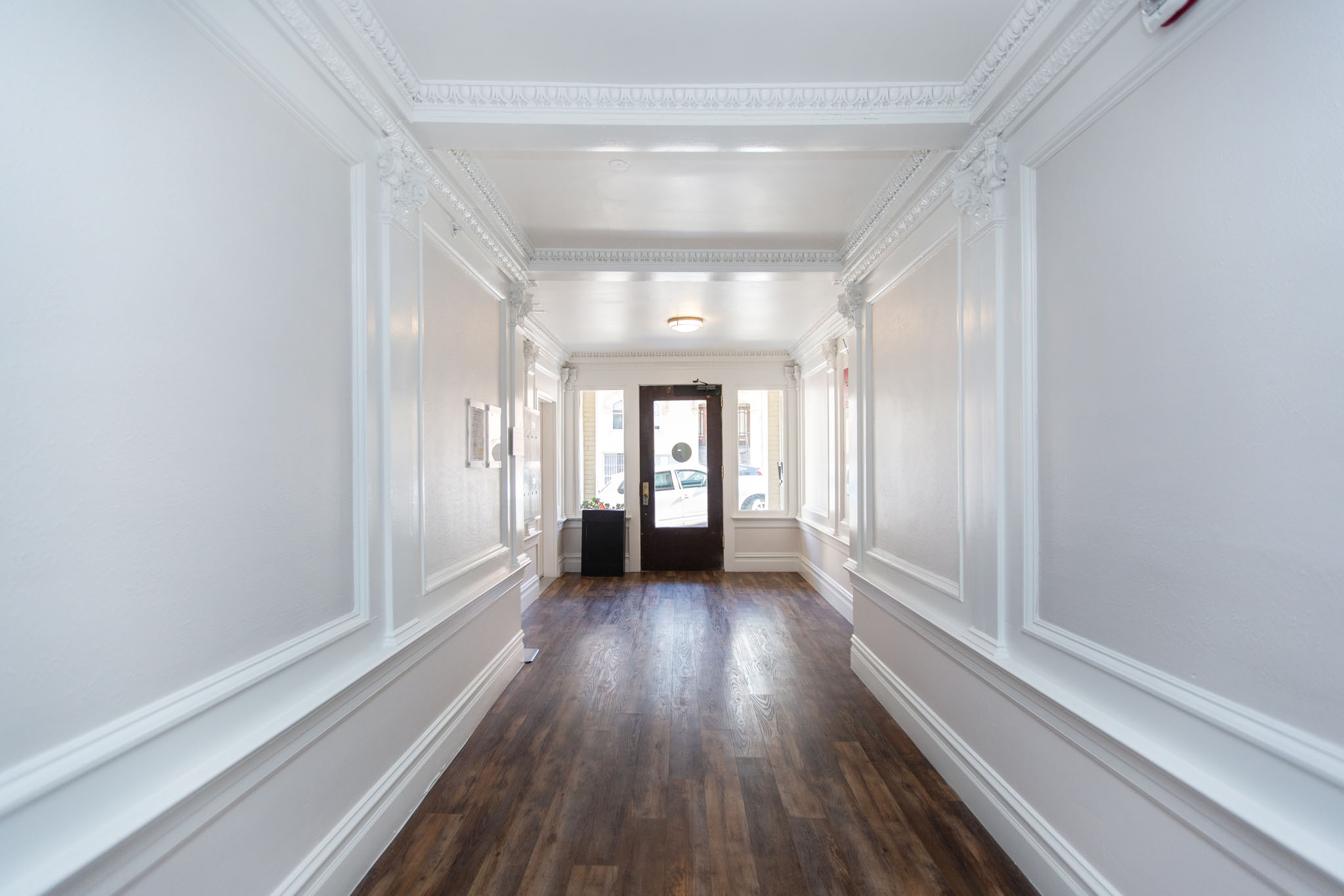 A long hallway with white walls and wood floors.