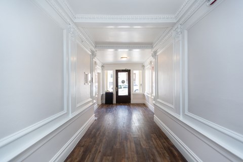 A long hallway with white walls and wood floors.