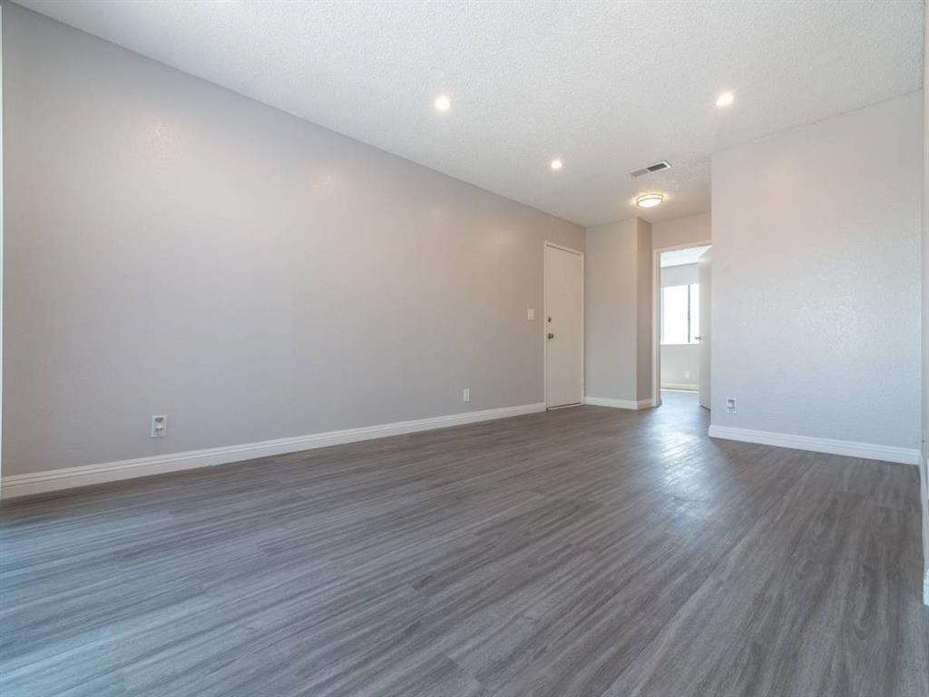 the living room and dining room of an empty home with wood flooring