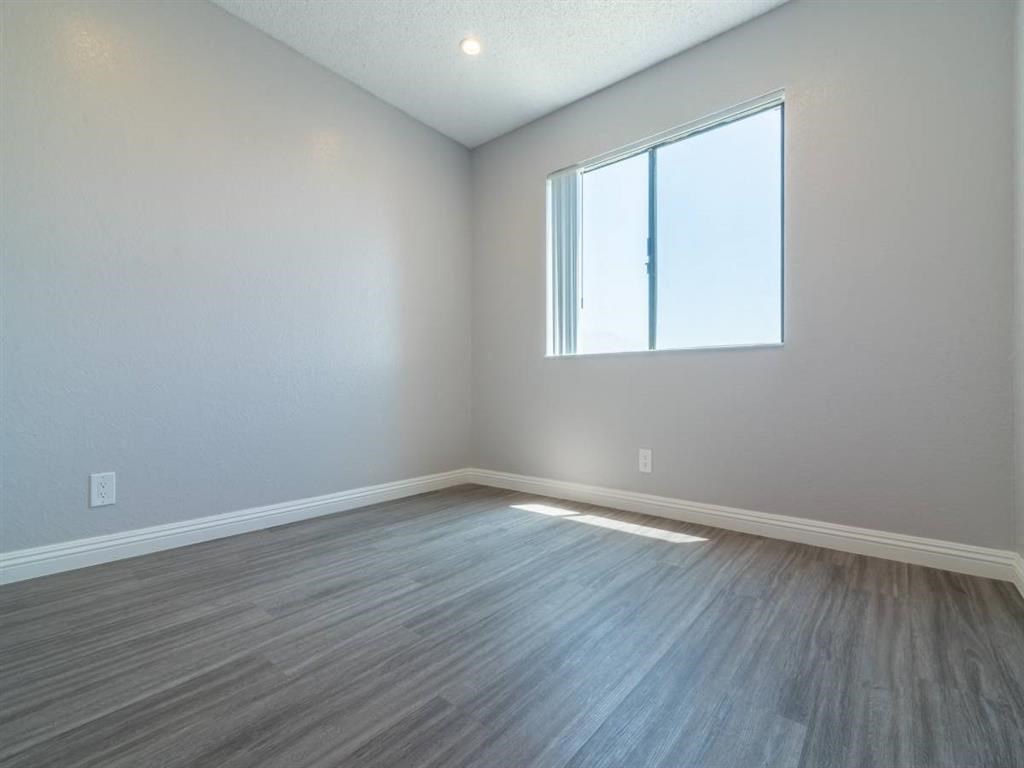 an empty living room with wood floors and a window
