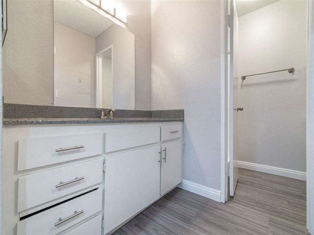 an empty bathroom with white cabinets and a mirror
