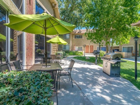 a patio with tables and umbrellas in front of a building