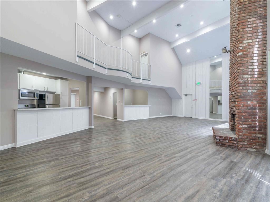 an empty living room with a brick wall and a kitchen