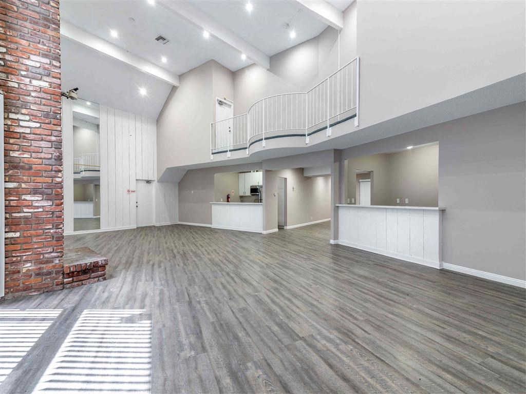 an empty living room with a brick wall and a staircase