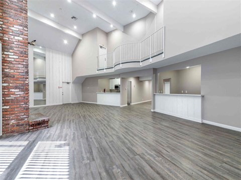 an empty living room with a brick wall and a staircase