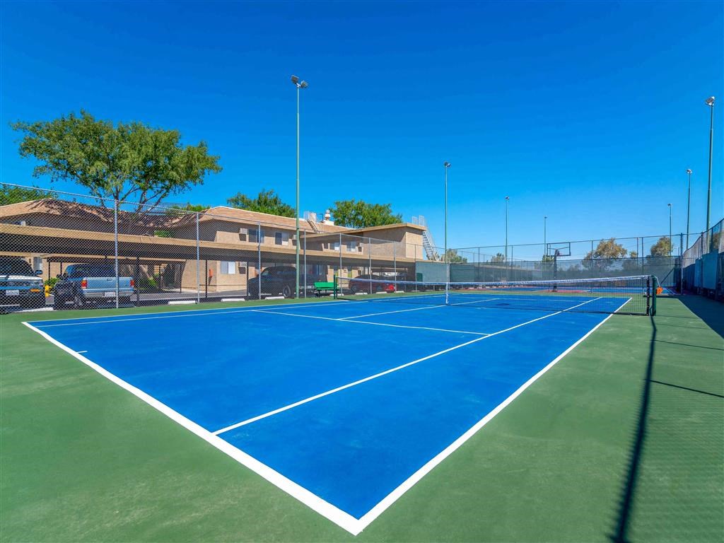 a blue and green tennis court with a building in the background