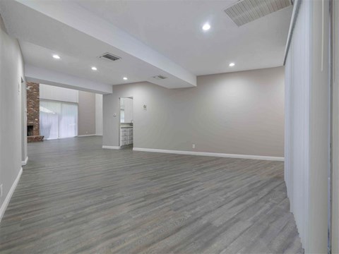 the living room and dining room of a house with white walls and wood floors