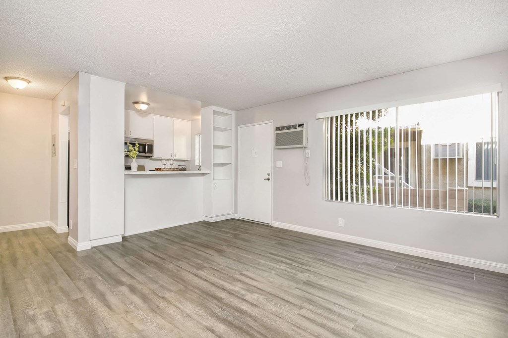 an empty living room and kitchen with a wood floor