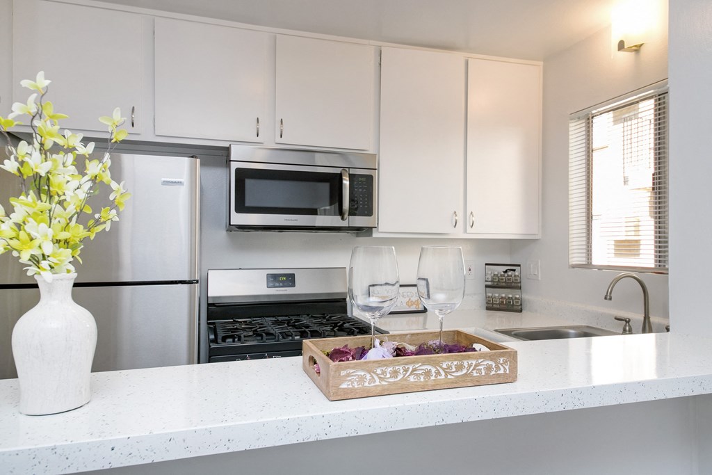 a kitchen with white cabinets and a counter with wine glasses