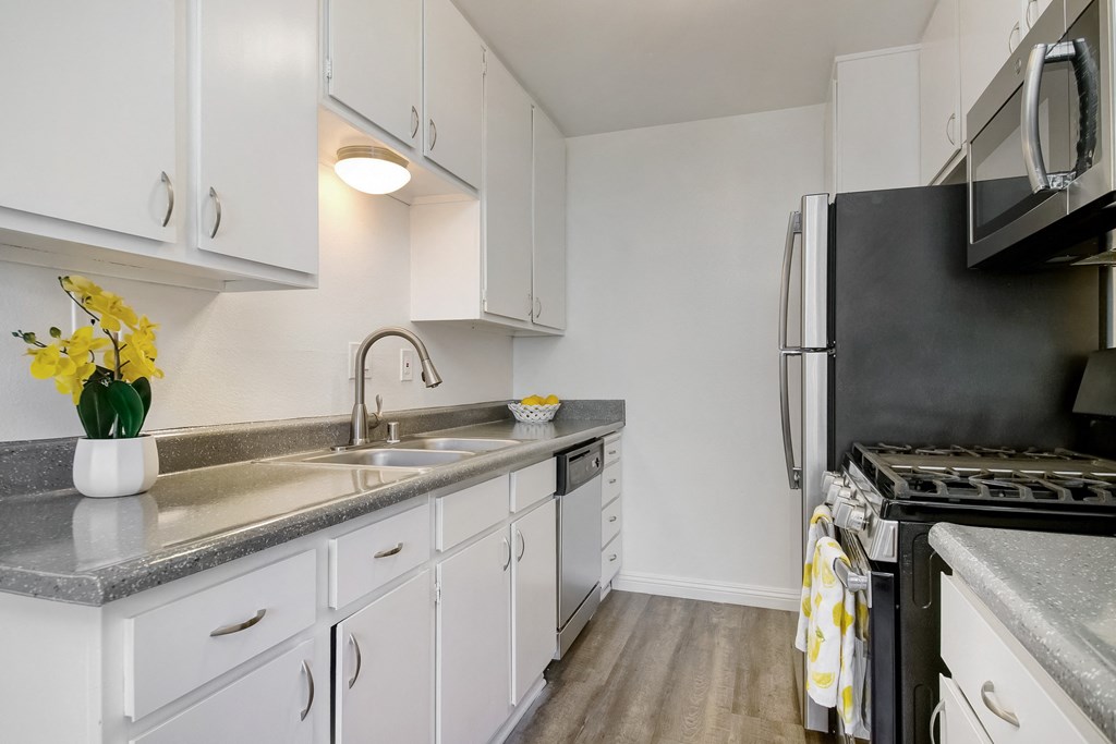 an apartment kitchen with white cabinets and stainless steel appliances