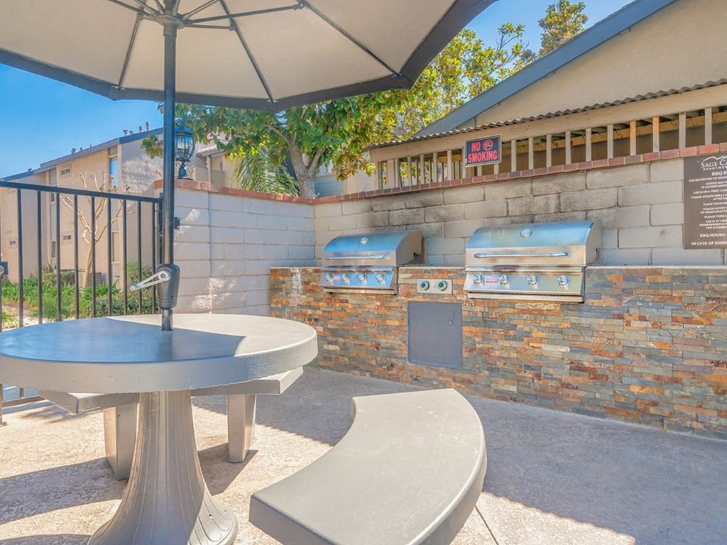 a patio with a table and chairs and a barbecue grill