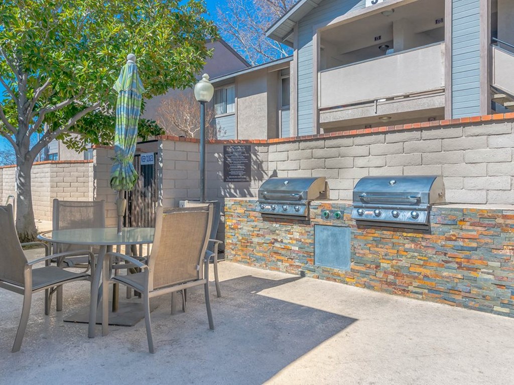 a patio with a barbecue grill and a table and chairs
