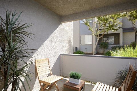 a balcony with two chairs and a table and a plant