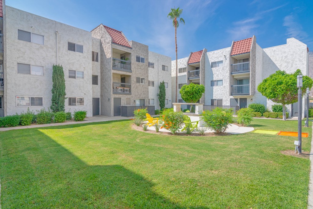 an apartment building with a green lawn and trees in front of it