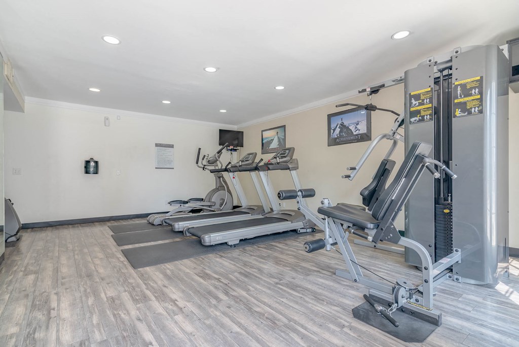 a gym with treadmills and weights in the corner of a room