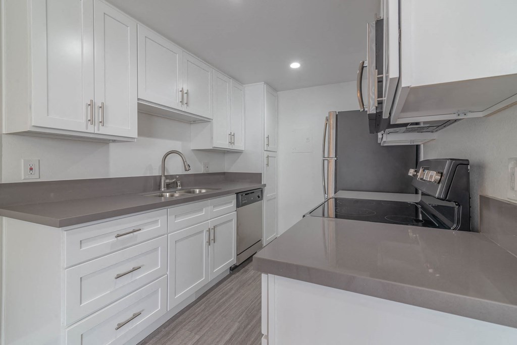 a kitchen with white cabinets and a sink and a refrigerator