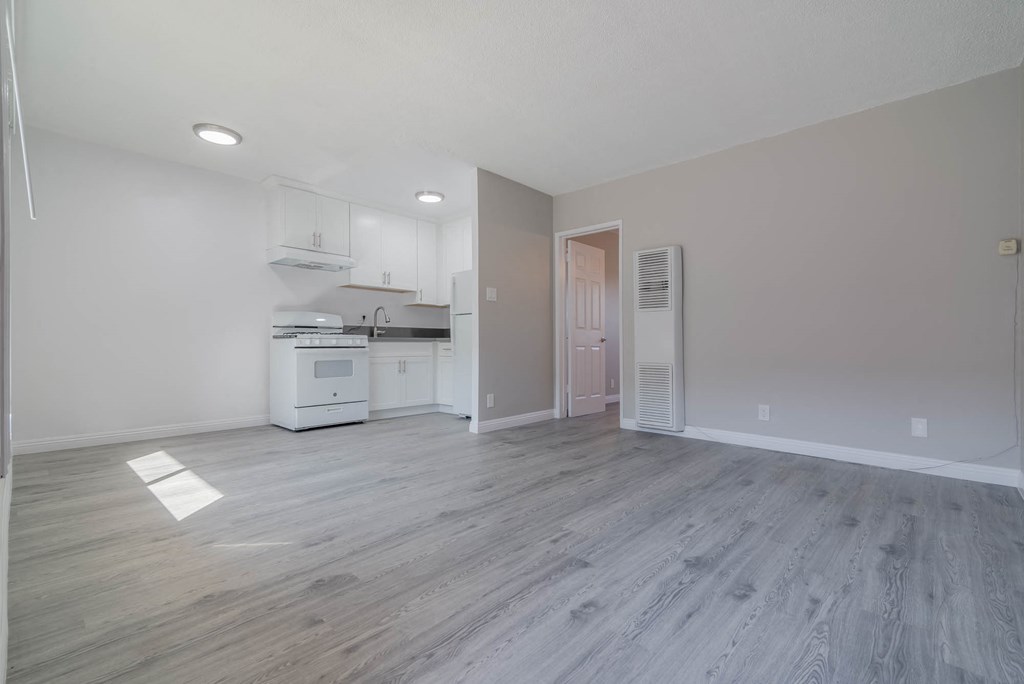 an empty living room and kitchen with white walls and wood floors