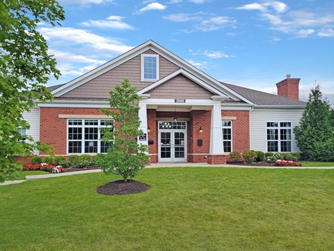 the front of a brick house with a lawn and a tree