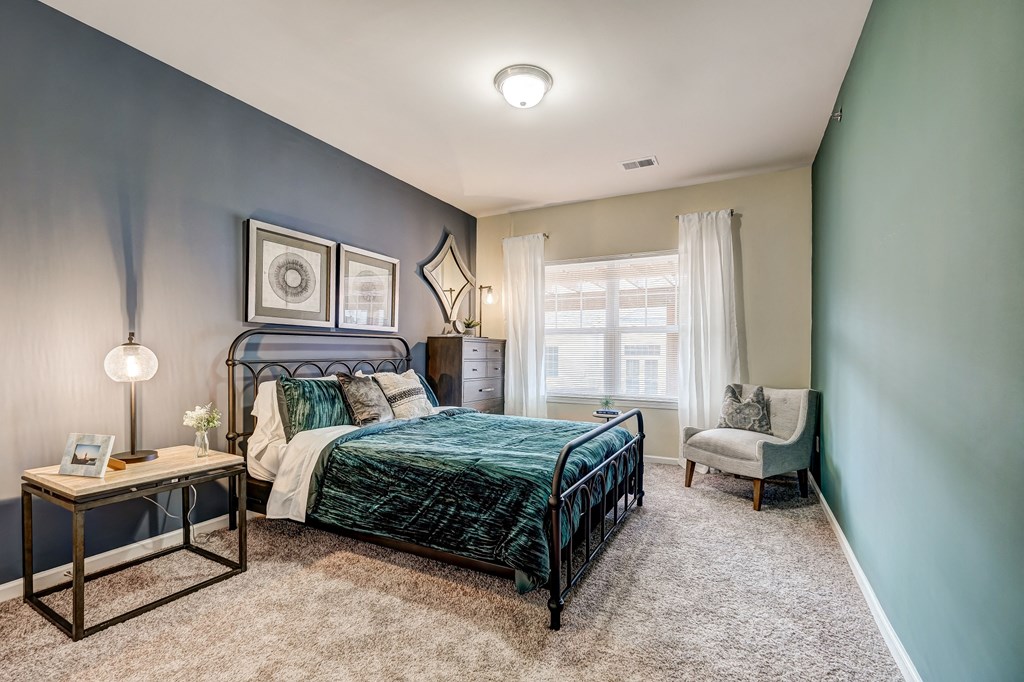 a bedroom with a bed and a chair and a window