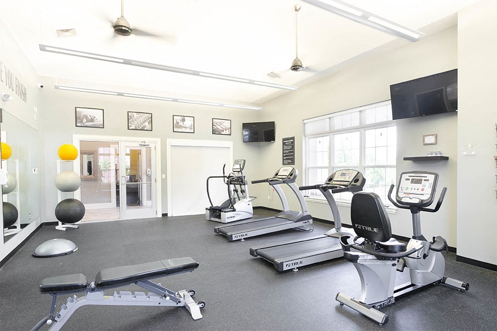 a gym with treadmills and other exercise equipment and a tv