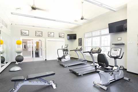 a gym with treadmills and other exercise equipment and a tv