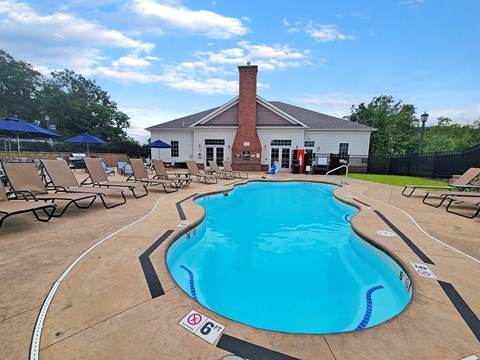 a pool with chairs and a building in the background