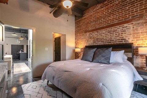 A bedroom with a large bed and a brick wall.