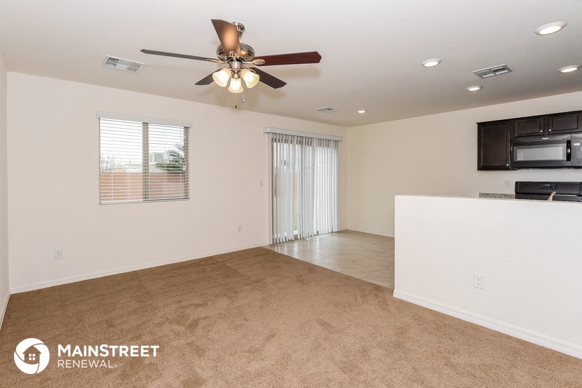 the living room and kitchen of a manufactured home with a ceiling fan