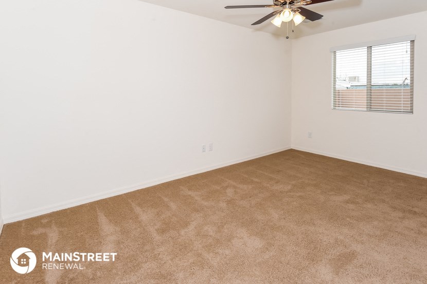 the spacious living room with carpeting and a ceiling fan