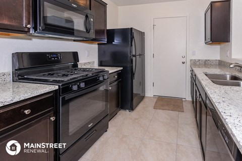 a kitchen with stainless steel appliances and granite counter tops and a black refrigerator